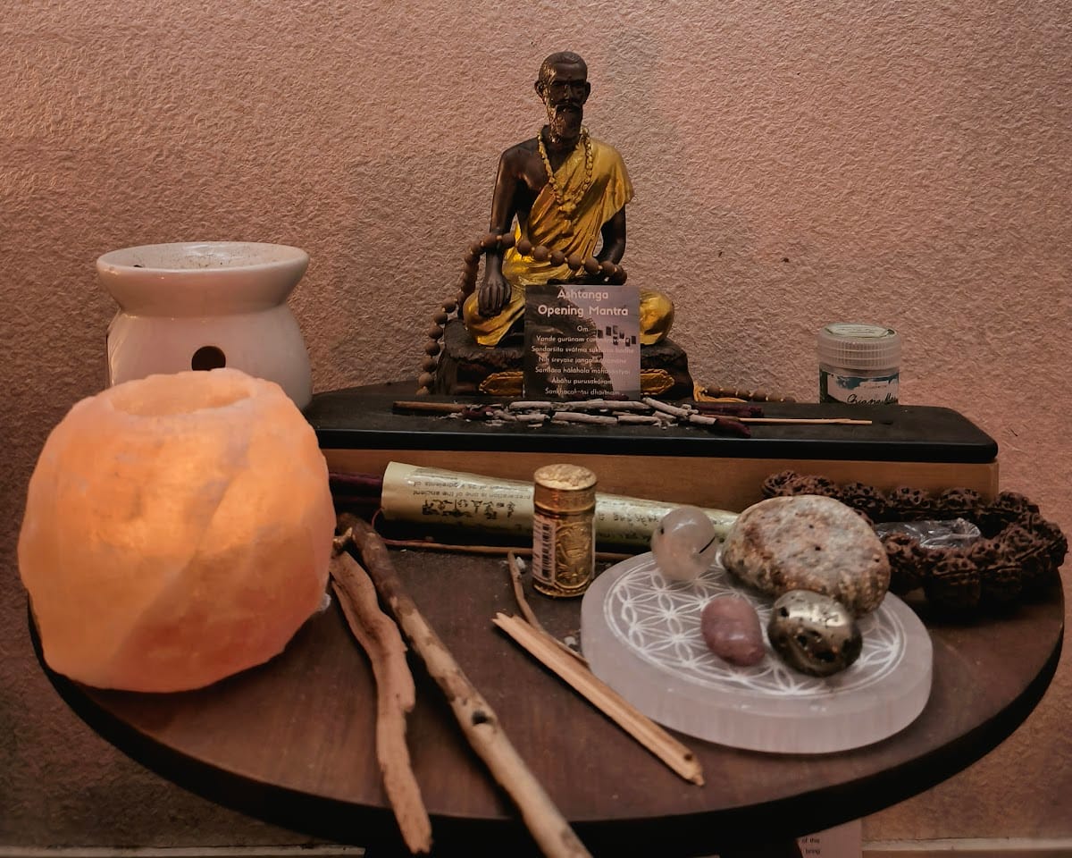 L'autel de la salle : une lampe de sel allumée, une statuette dorée, de l'encens, des pierres et des cristaux sur une petite table ronde en bois.